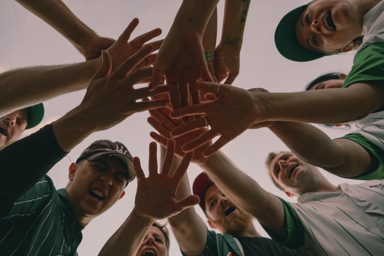 Outfielders teammates bringing their hands together in a team huddle